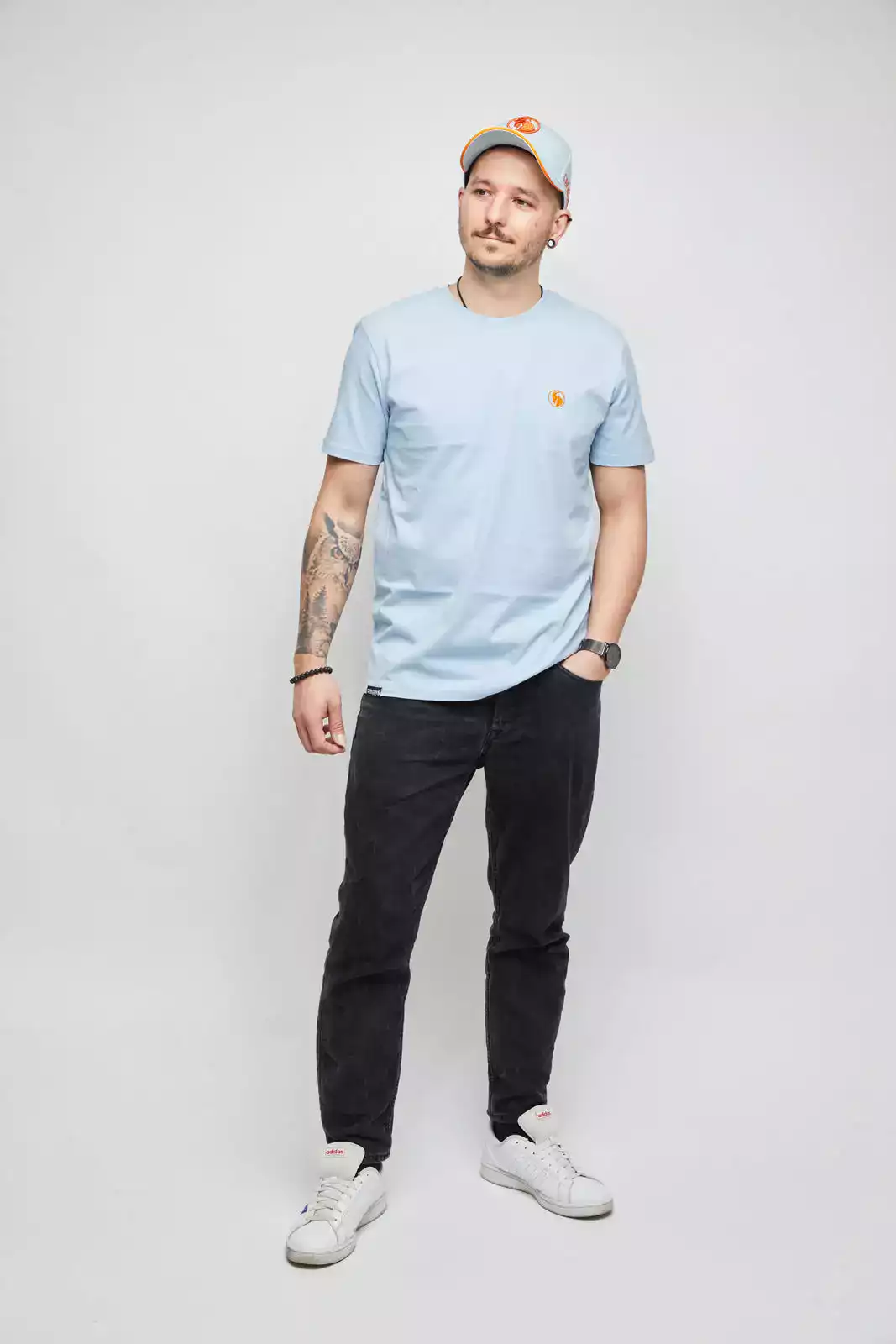 mönnliches Model mit hellblauem T-Shirt und hellblauer Baseball Cap. Studioaufnahme