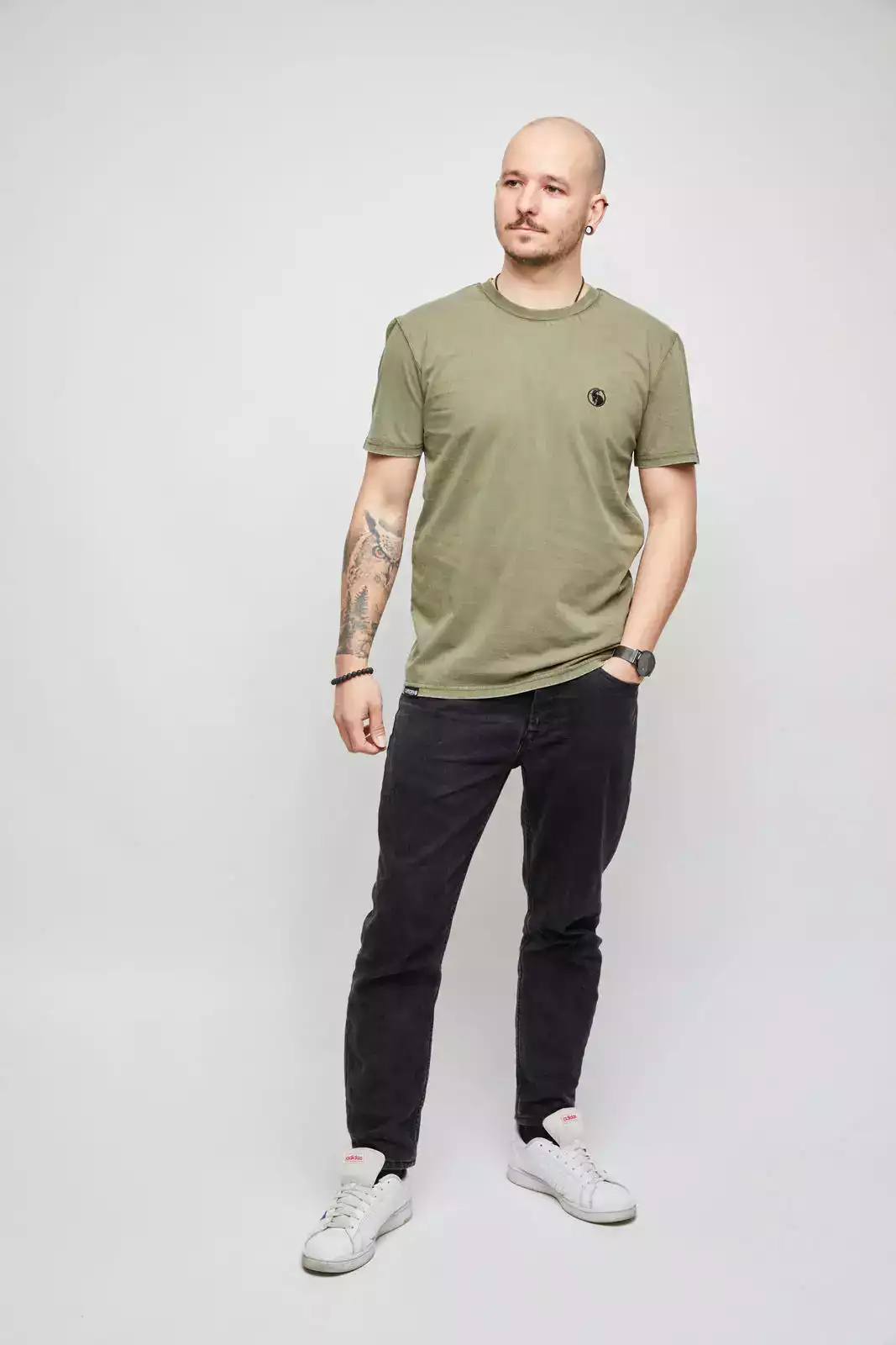 Mann trägt olivgrünes T-Shirt mit schwarzem Stick. Vorderansicht.