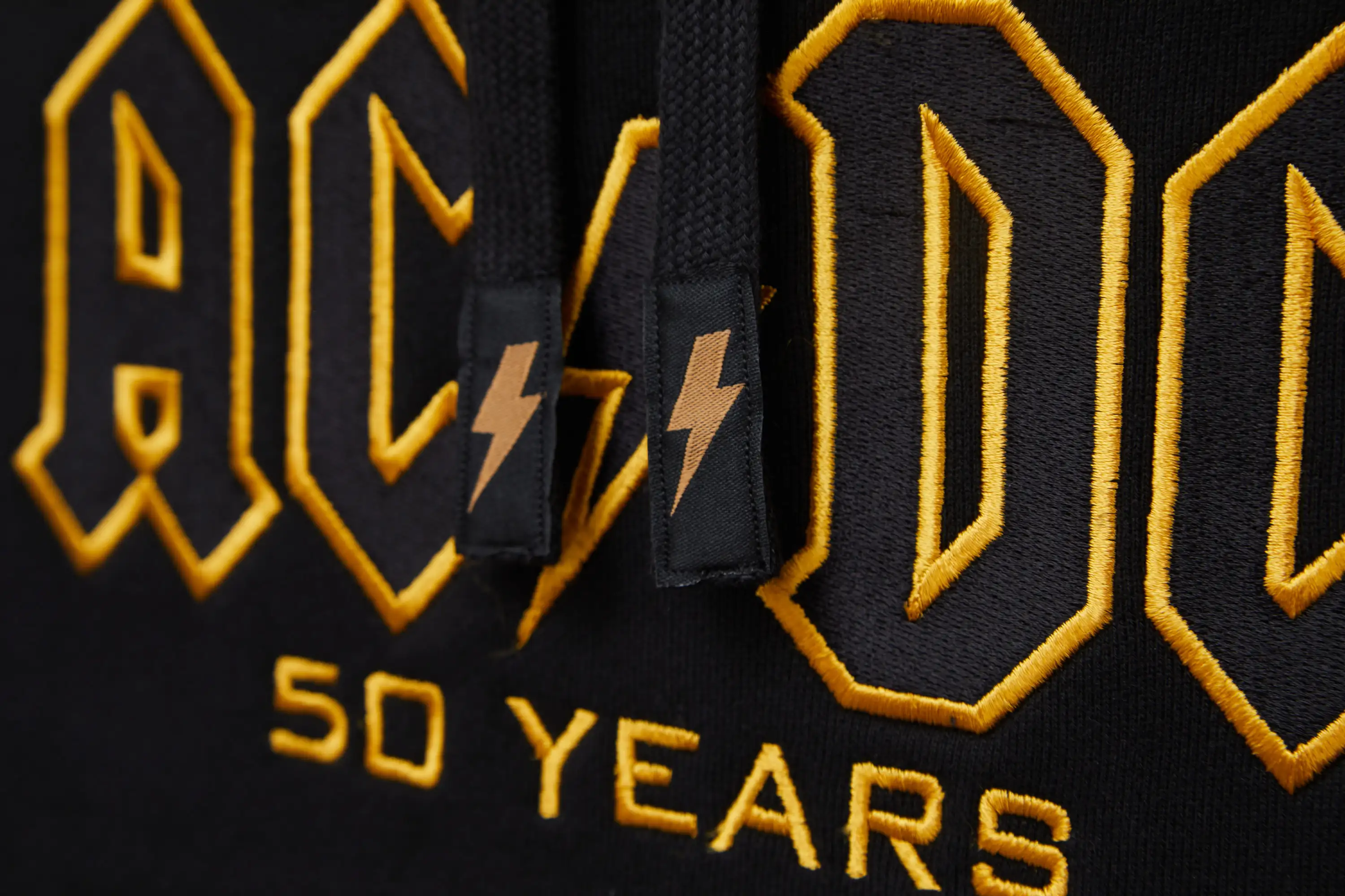 AC/DC Hoodie Detailansicht gesticktes Logo in schwar gold auf der Brust