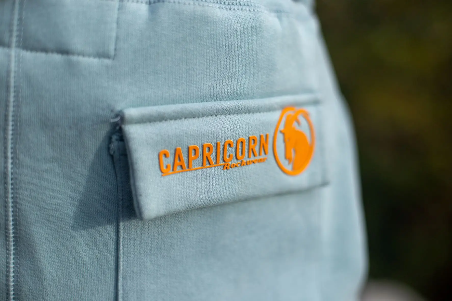 Taschendetail hellblaue Hose mit orangefarbenem Logo Rubberprint