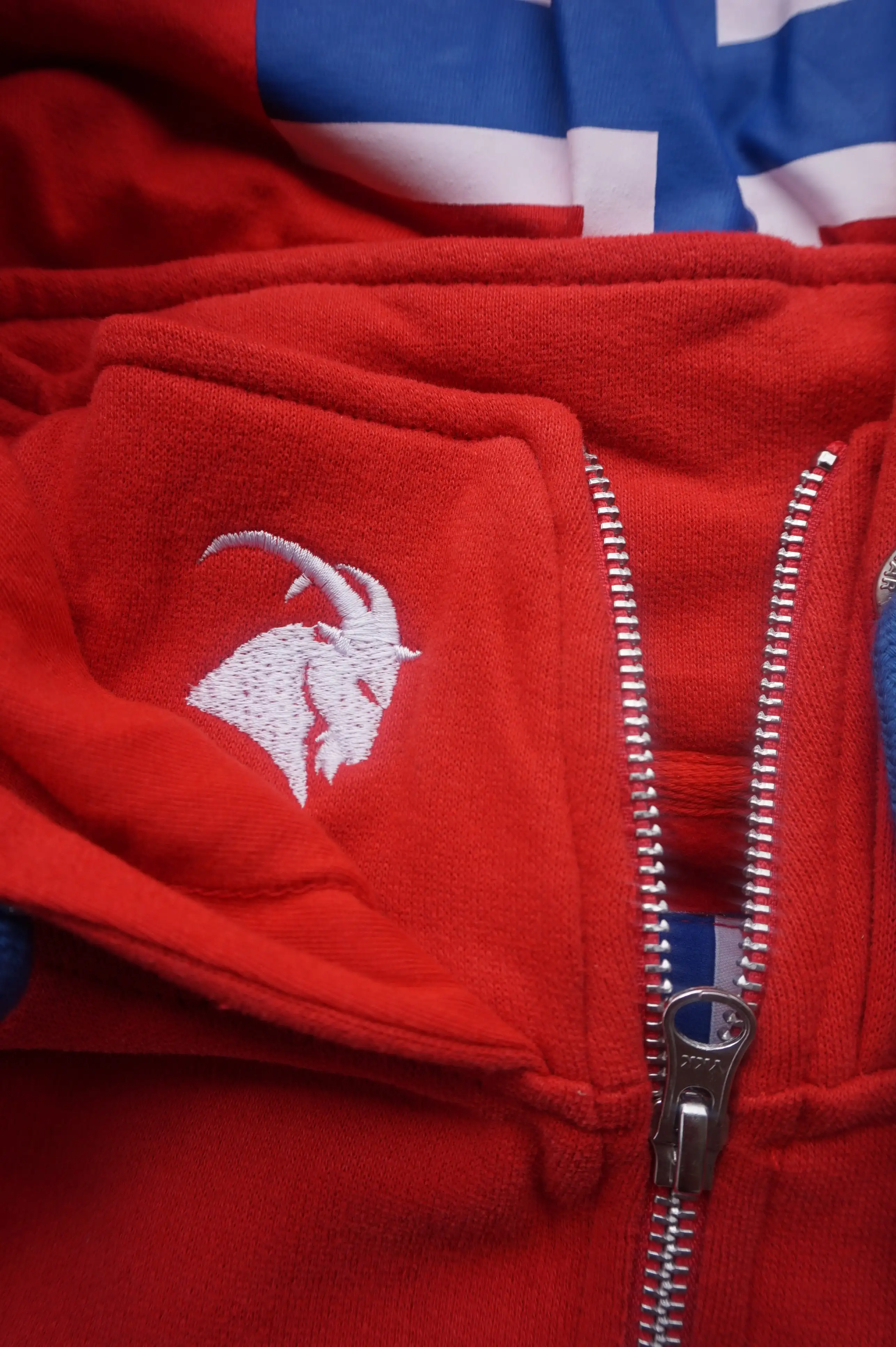 Kapuzenjacke in rot mit weißem Steinbock Kopf auf Kragen