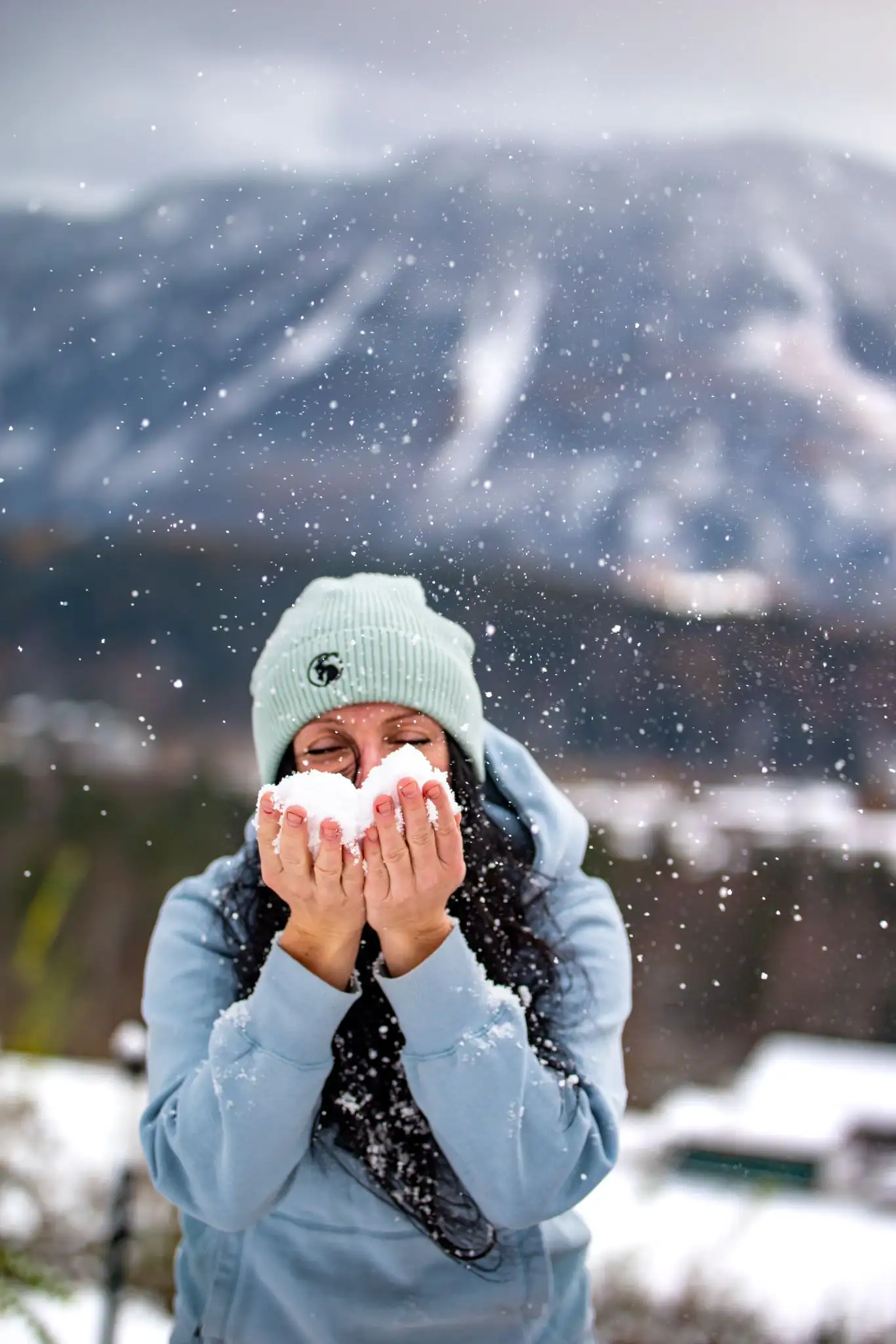 Model mit hellgrüner Beanie und Schnee im Gesicht