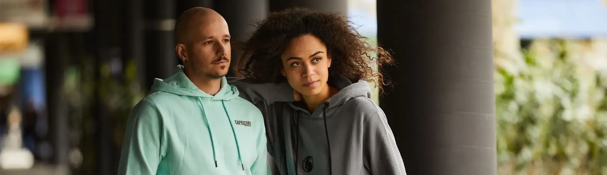 Männliches model im mintfarbenem Hoodie und weibliches Model mit grauem Hoodie