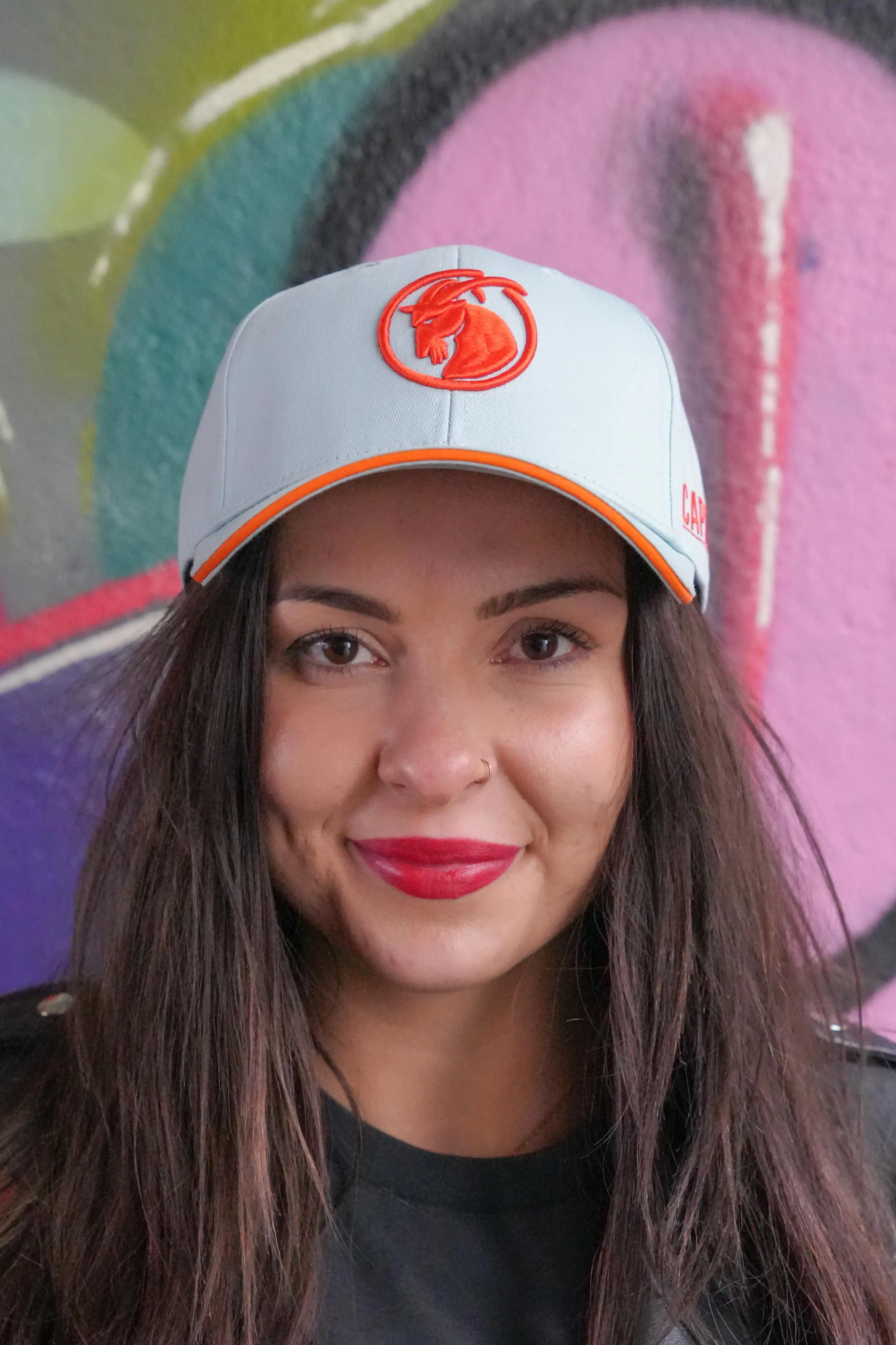 hellblaue Baseballcap mit orangefarbenem Steinbock von Frau getragen