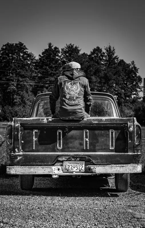 Mann mit Motörhead Jacke sitzend auf Ford Pick-up. Rückansicht