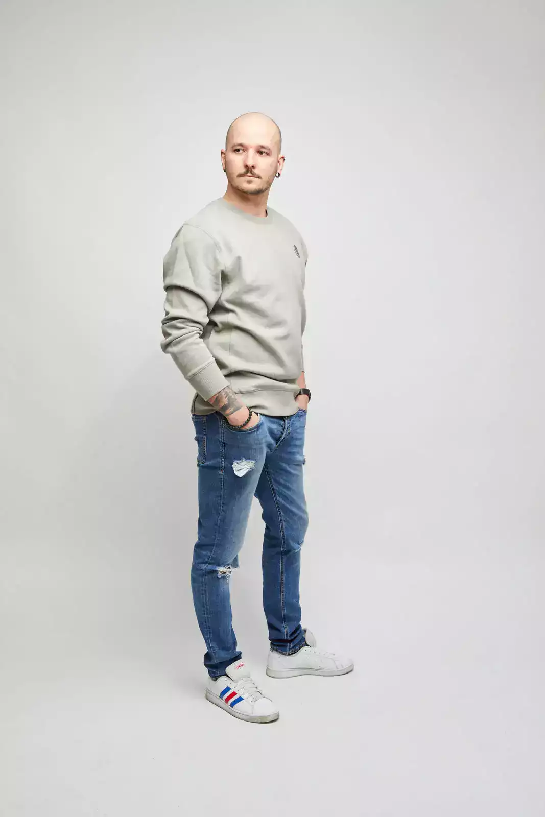 Männliches Model trägt hellgraues Sweatshirt. Seitenansicht von rechts