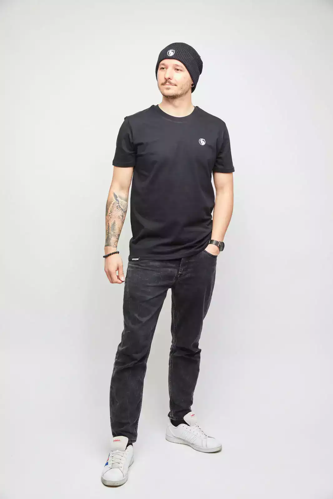 Männliches Model mit schwarzem T-Shirt und schwarzer Beanie. Studioaufnahme