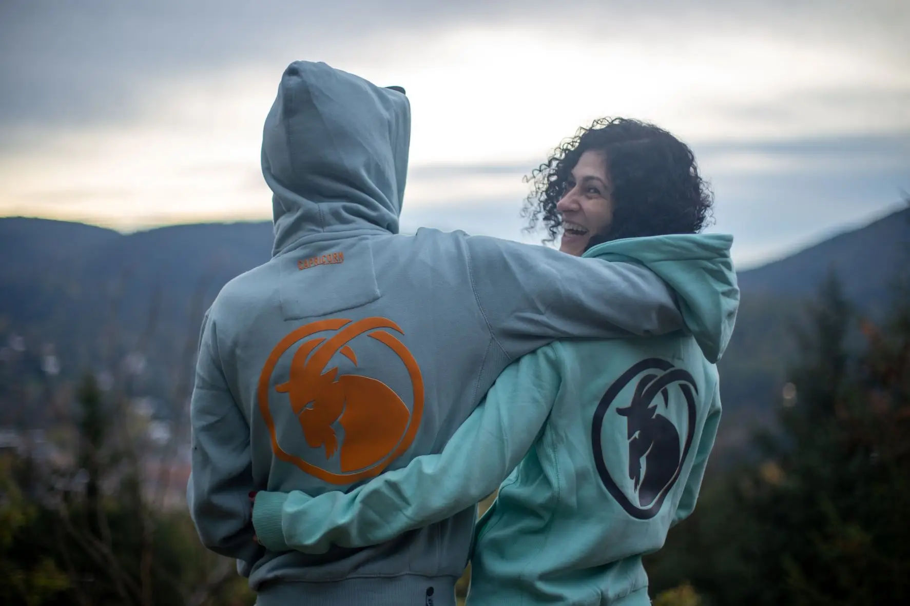 männliches und weibliches Model mit hellblauen und mintgrünen Kapuzenjacken.