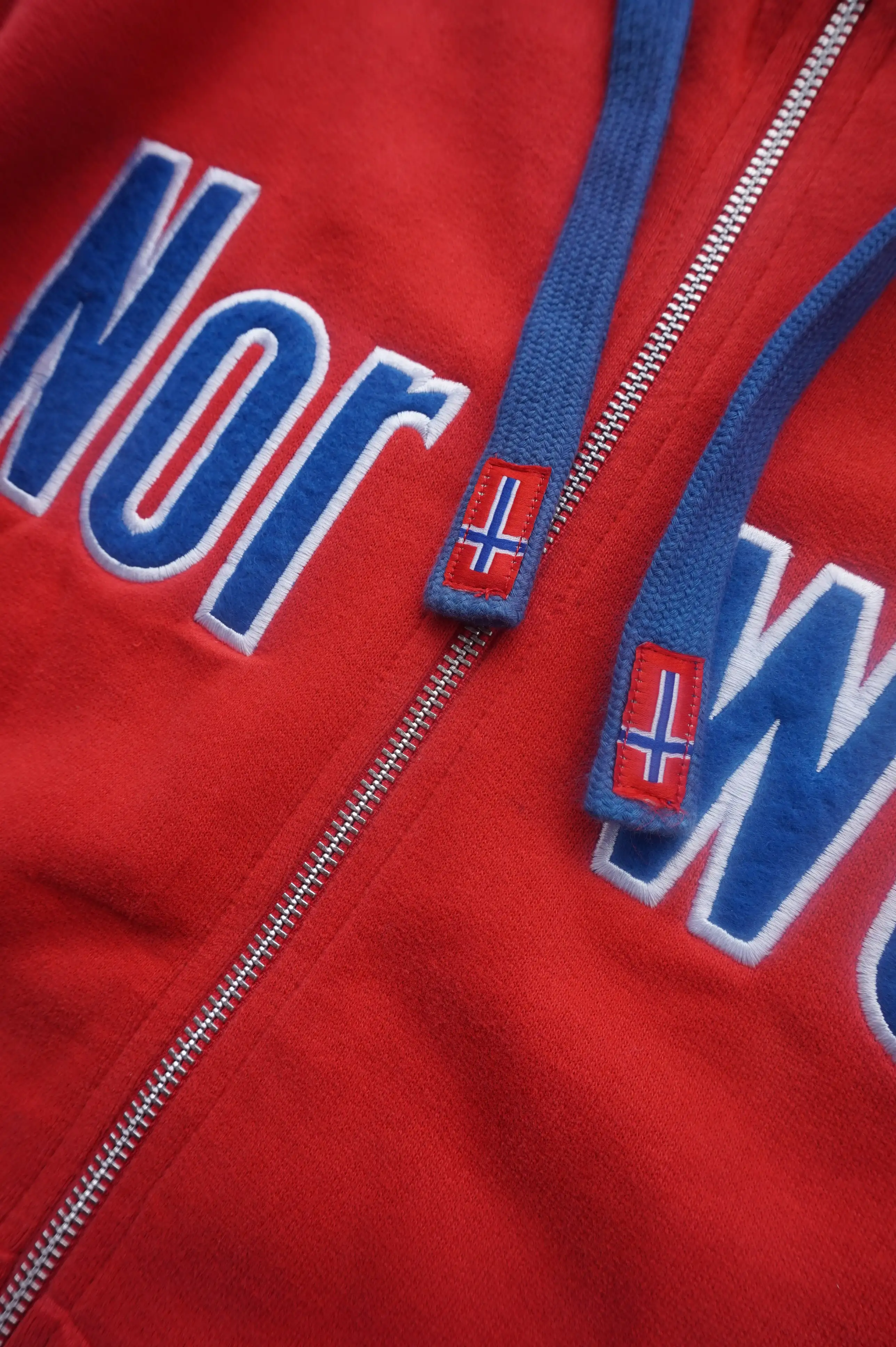 Kapuzenjacke rot mir blauem Norway Schriftzug auf der Brust. Detailansicht
