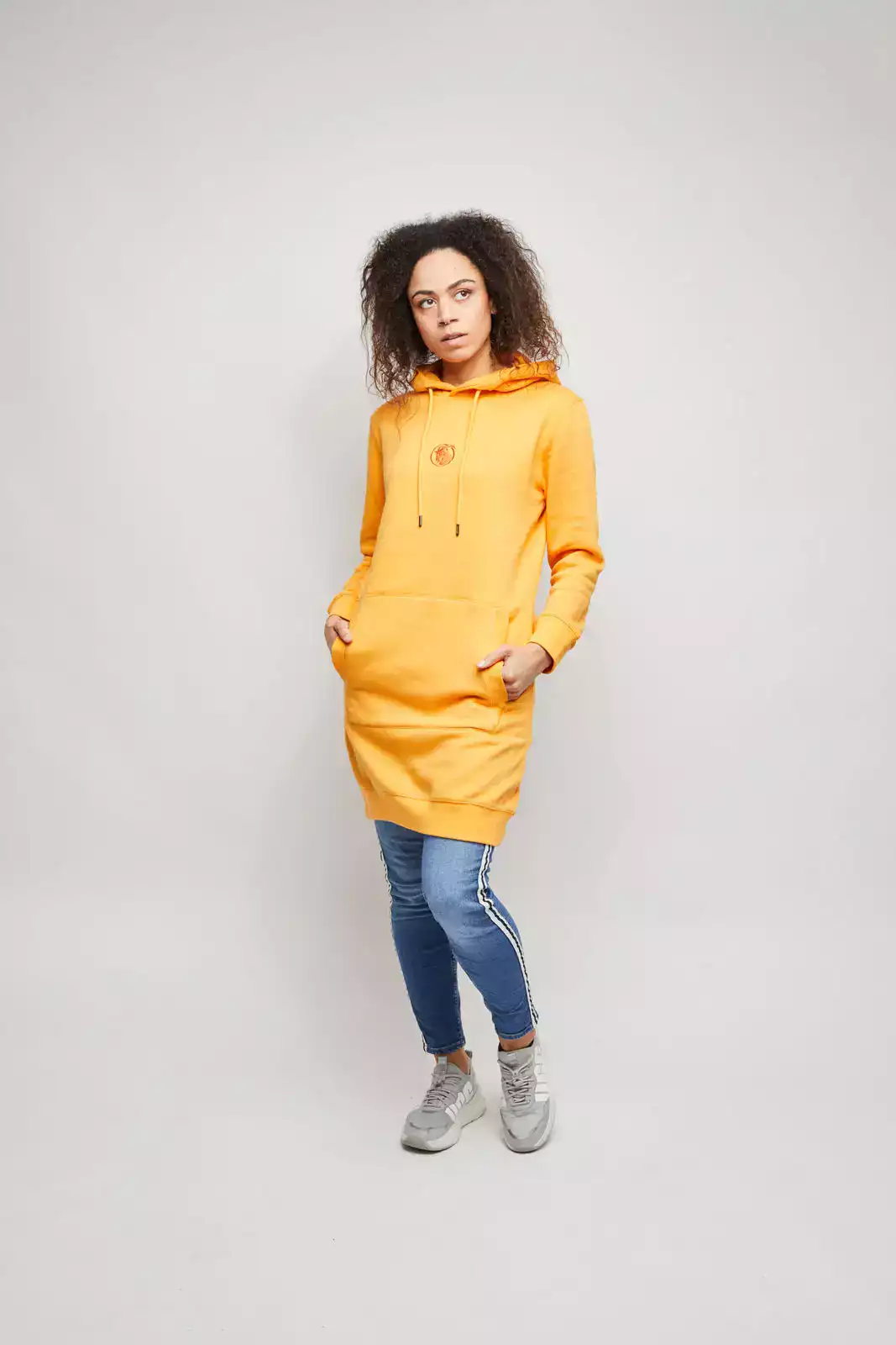 Model trägt orangefarbenes Sweatkleid. Studioaufnahme