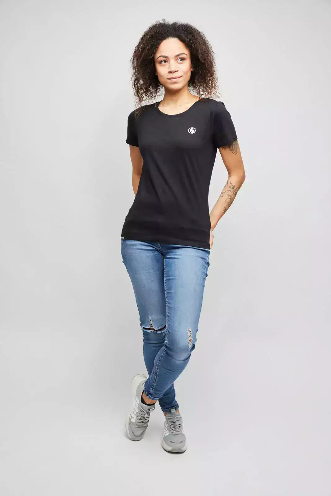 Frau trägt schrzes T-Shirt mit weißem Logo Stick auf der Brust.