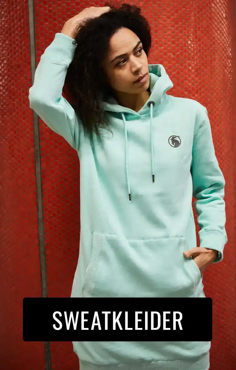 Frau trägt mintfarbenes Sweatkleid vor roter Säule stehend