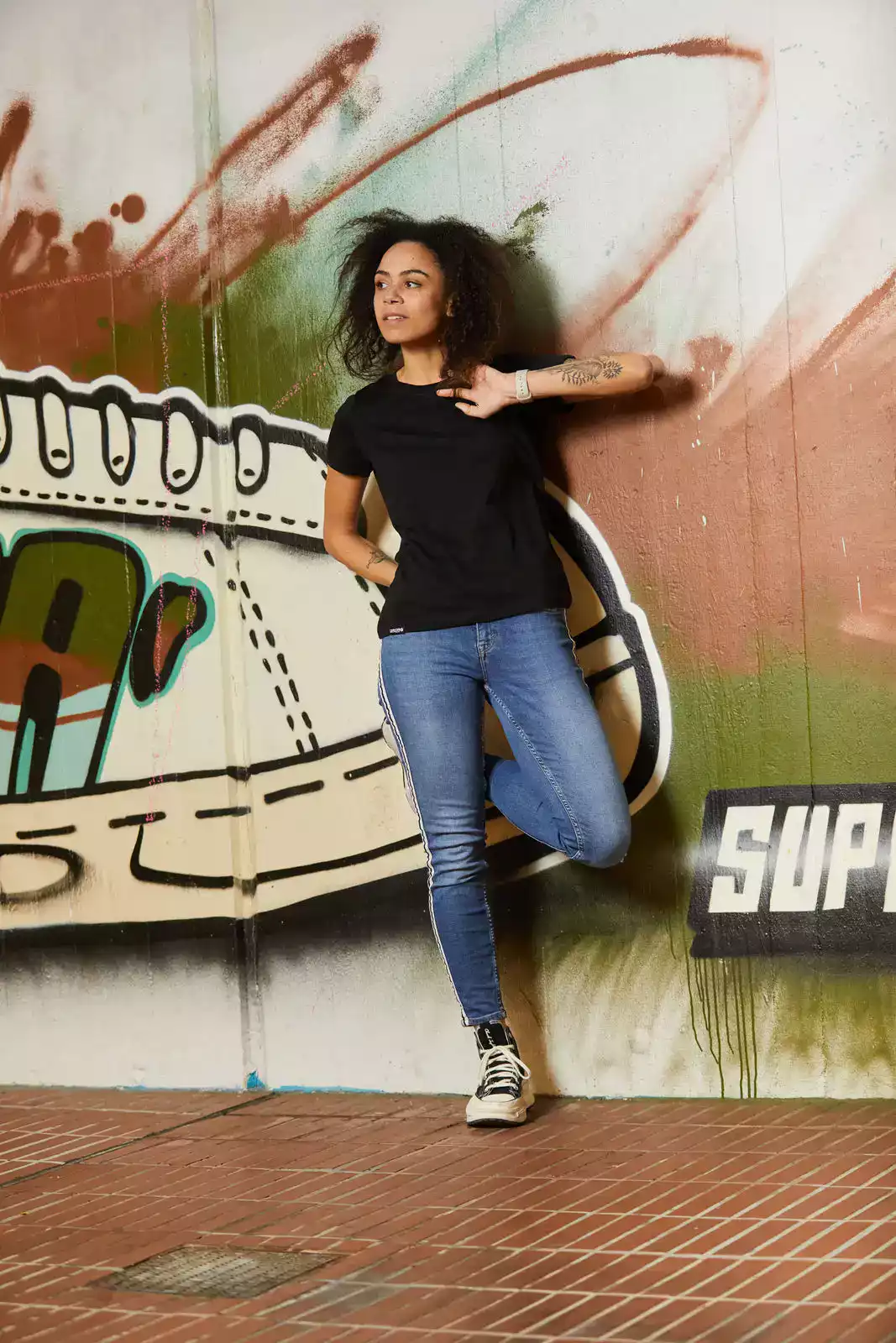 Frau mit schwarzen T-Shirt vor Graffiti Wand