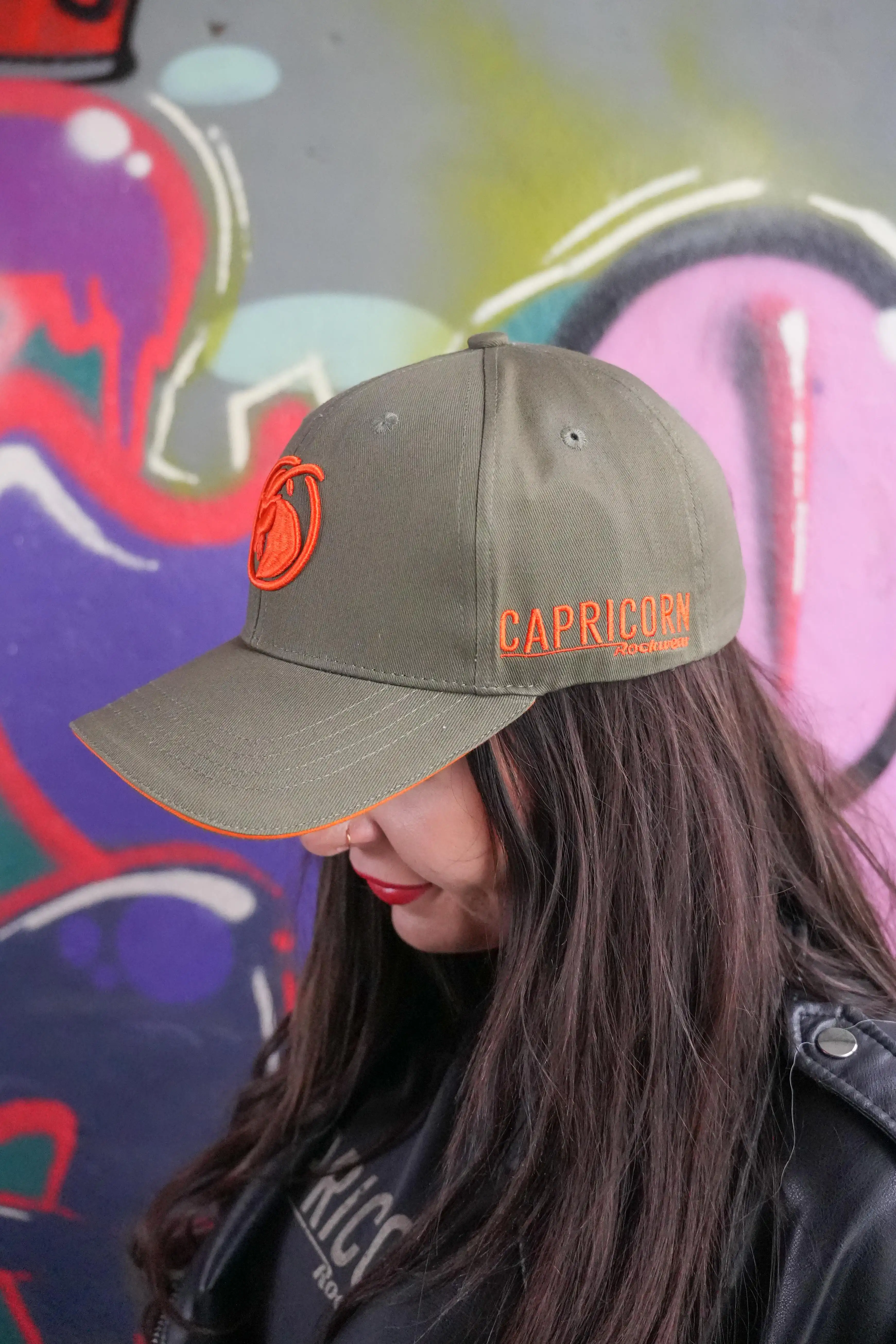 olivfarbene Baseballcap mit orangefarbenem Schriftzug an der Seite
