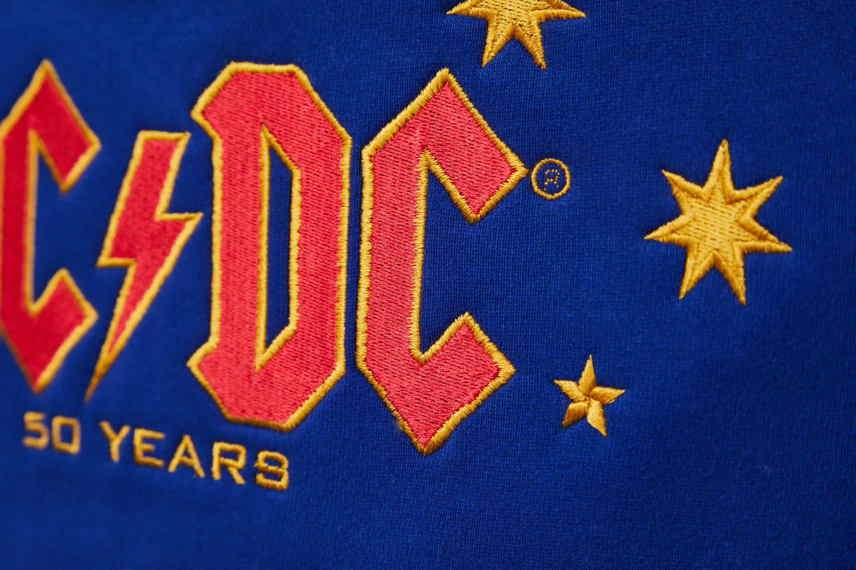 Detalansicht Rückenstick, AC/DC Logo in rot gold mit Sternen
