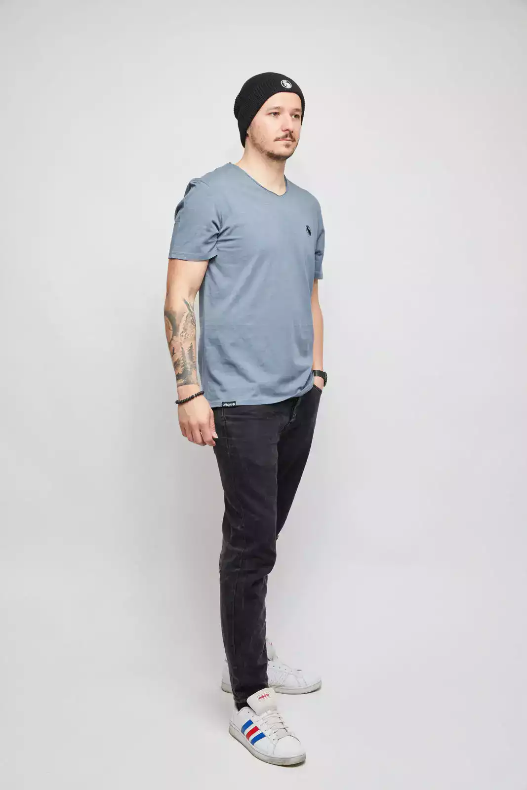 Mann mit grauen T-Shirt und schwarzer Beanie. Studioaufnahme