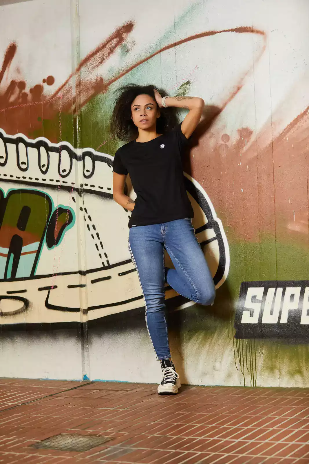 Frau trägt schwarzes T-Shirt und geht sich mit der Hand durch die Haare